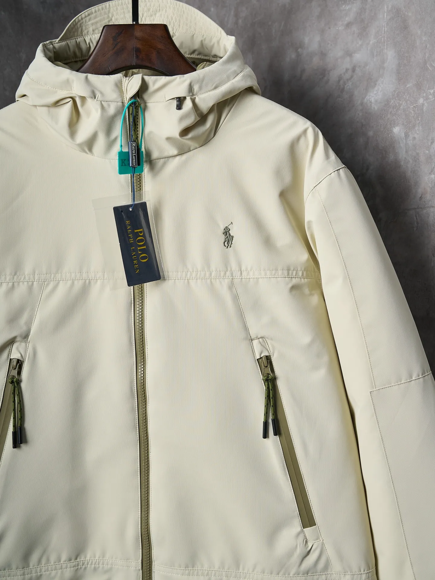P980 Actual auction】Ralph Lauren/Ralph Lauren pony embroidered zipper hooded down jacket [Ready stock] S M L XL high-quality filling: 90 white duck down is selected, weighing 220g, ensuring excellent thermal insulation performance. After strict screening and processing, the velvet is not easy to be drilled, ensuring durability. The density of high-density nylon taffeta is about 210T-300T, with a smooth and slightly matte surface, excellent windproof and waterproof properties (with DWR water-repellent treatment), strong wrinkle resistance and easy care, in line with the positioning of American casual "durable and practical".  The inner lining is made of 100% polyamide. The high-density and tight weaving process prevents fine lint from getting out of the gaps in the fabric. The smooth surface improves the putting on and taking off experience, and the excellent wear and tear resistance ensures damage caused by frequent use, while the light and soft texture does not affect the overall weight.  The classic jacket has a slightly loose fit, slightly dropped shoulder line (shoulder width is 1-2cm wider than the standard fit), is hip-length, and has slightly tapered straight sleeves, taking into account both freedom of movement and casual style.  The adjustable Velcro on the cuffs allows you to freely adjust the tightness according to the thickness of your wrist and personal preferences, effectively preventing cold wind from intruding, and improving the warmth performance.  In terms of storage, the two front zipper pockets are convenient for you to place frequently used items, and the zipper design ensures that items are not easily lost. A built-in pocket on the left side of the chest provides a safe storage space for some small private items.  The drawstring design at the hem allows you to adjust the shape of the jacket according to your body shape and dressing needs. Whether it is loose and casual or slim and neat, you can easily control it.  Embroidery technology: Polo horse logo on the left chest: flat satin stitch embroidery (satin embroidery), embroidery thread: 100% polyester high color fastness embroidery thread (the color number is consistent with the brand’s standard red color card), stitch density 12-15 stitches/cm, the outline of the horse logo is clear, and the details of the rider and horse are burr-free.  Embroidery positioning: precise positioning through the template (12cm from the neckline and 8cm from the placket) to ensure left and right symmetry and centering.